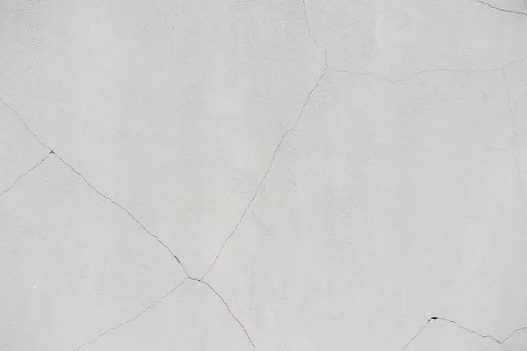 Close view of fine cracking spreading across a pale stucco wall