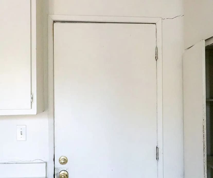 Interior door sitting out of square with a crack running up the wall beside its frame