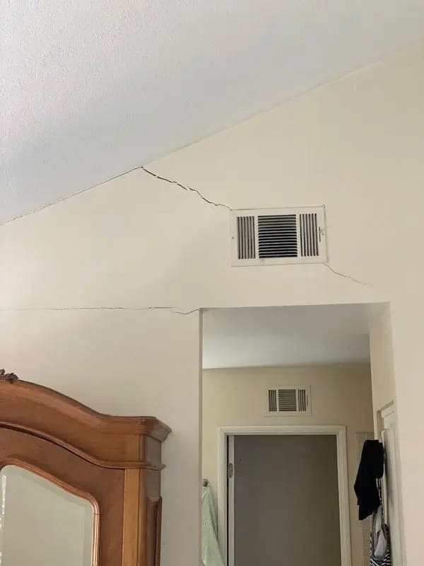 Crack opening along the line where an interior wall meets the ceiling above a doorway