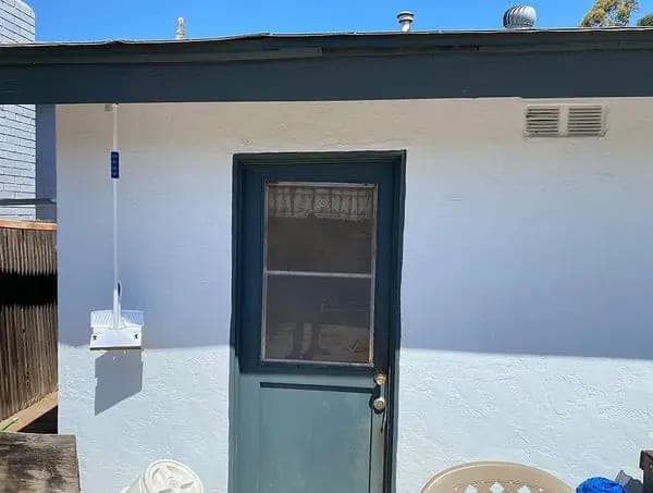 Exterior door sitting out of square in its frame in a stucco wall