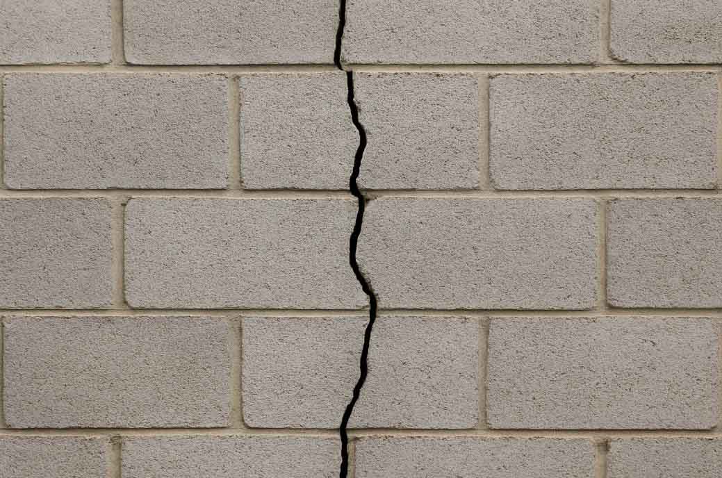 Vertical crack running straight down through the courses of a cinder block wall