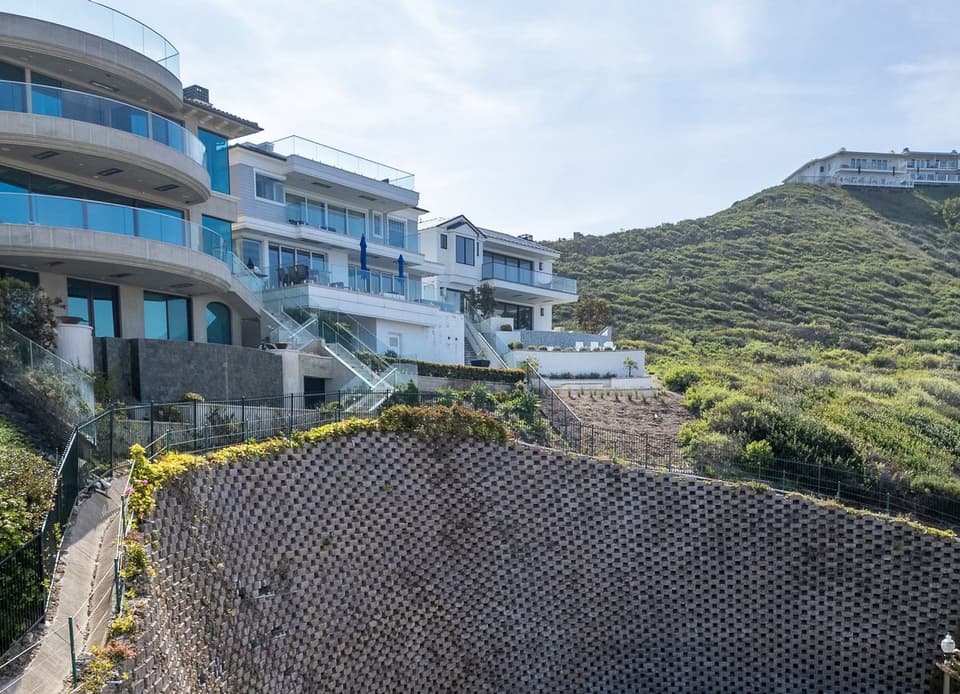 Tall block retaining wall holding back a hillside below a row of homes