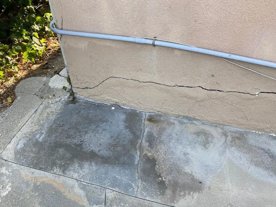Long horizontal crack running through a concrete wall at ground level