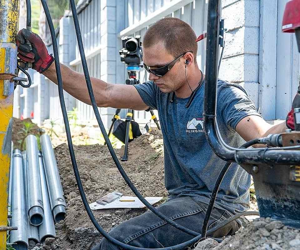 Dalinghaus technician working at a row of steel pier tubes laid out beside an excavated footing