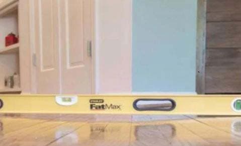 Level laid across a wood floor beside a doorway to check it for slope