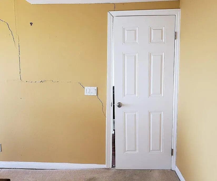 Interior door out of square in its frame with a crack running up the wall beside it