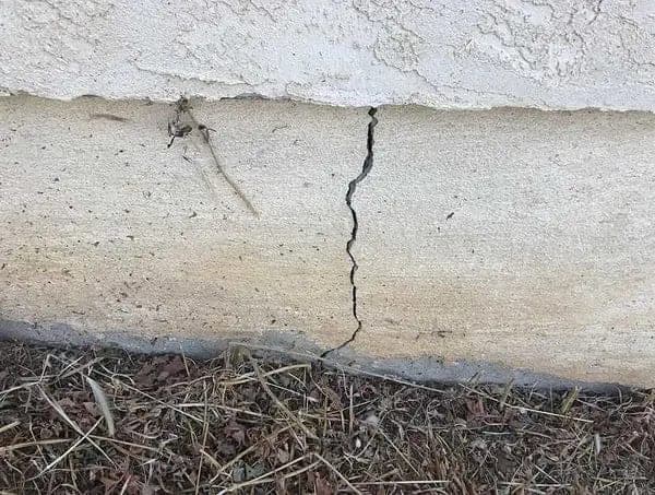 Vertical crack opening through a concrete footing at the base of a stucco wall