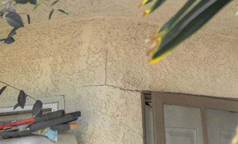 Crack running across a stucco wall from the corner of a window frame