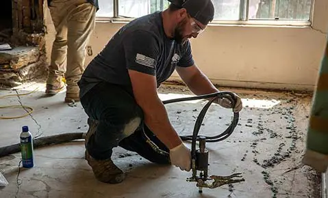Dalinghaus technician injecting polyurethane foam into an interior concrete floor