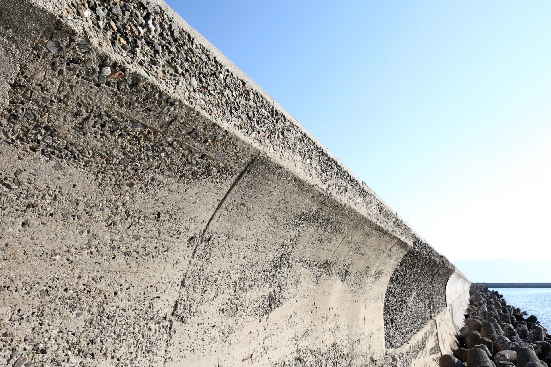 Dalinghaus Foundation Repair inspecting a cracked seawall with visible concrete damage and ocean in the background.