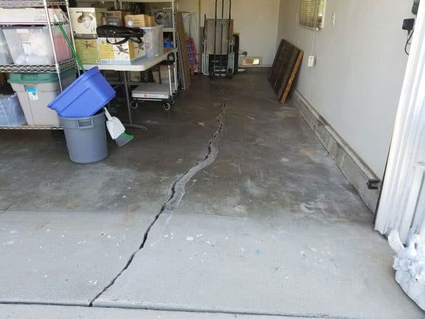 Dalinghaus Foundation Repair inspecting a large, distinct crack in a concrete garage floor.