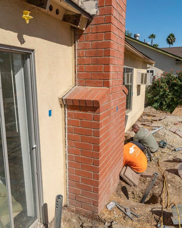 Dalinghaus Foundation Repair workers beginning a chimney foundation repair for a chimney pulling away from a house.