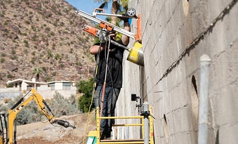 Dalinghaus Foundation Repair technician installing helical tie-back anchors into a concrete wall for retaining wall stabiliza