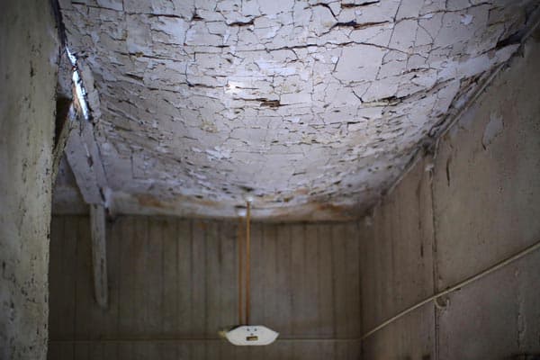 Dalinghaus Foundation Repair inspecting severe cracks and peeling paint on a sagging ceiling.