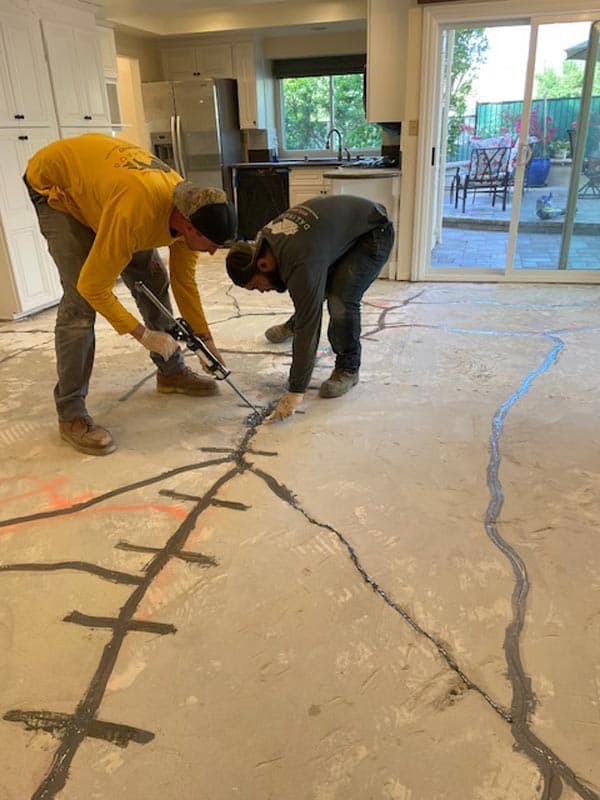 Dalinghaus Foundation Repair technicians injecting epoxy into cracks in an interior concrete floor.