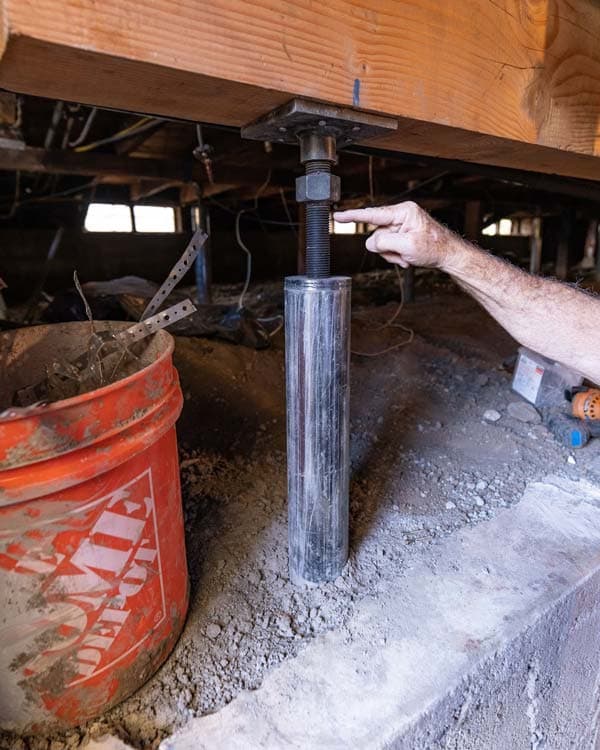 Dalinghaus Foundation Repair technician adjusting an adjustable crawl space support jack to stabilize sagging floor joists.
