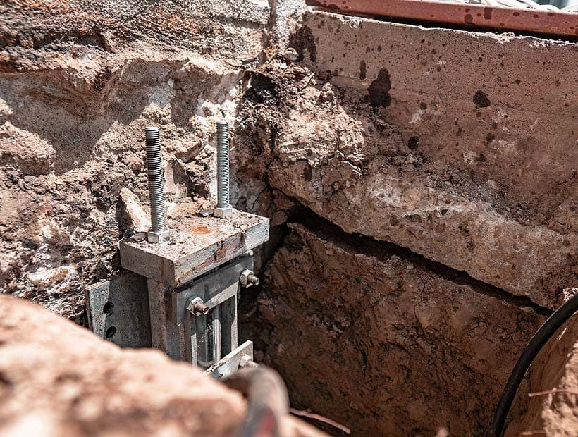 Dalinghaus Foundation Repair installing adjustable foundation jacks and support posts into a concrete foundation wall with a