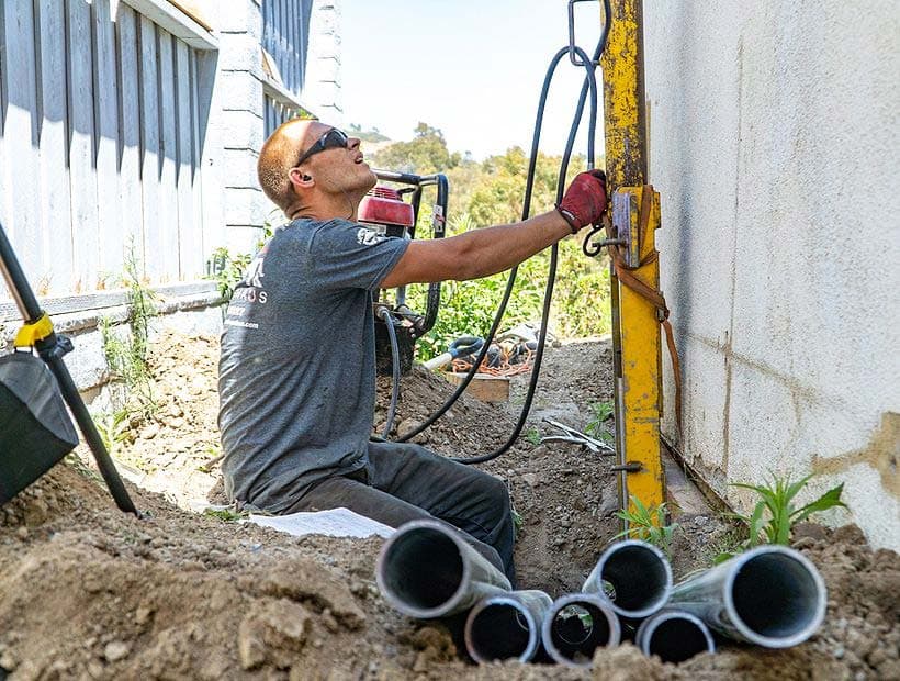 Dalinghaus Foundation Repair technician installing hydraulic push piers for foundation stabilization.