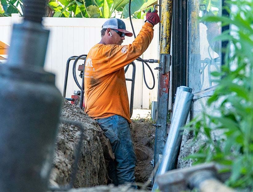 Dalinghaus Foundation Repair technician installing hydraulic push piers for foundation stabilization in a trench.