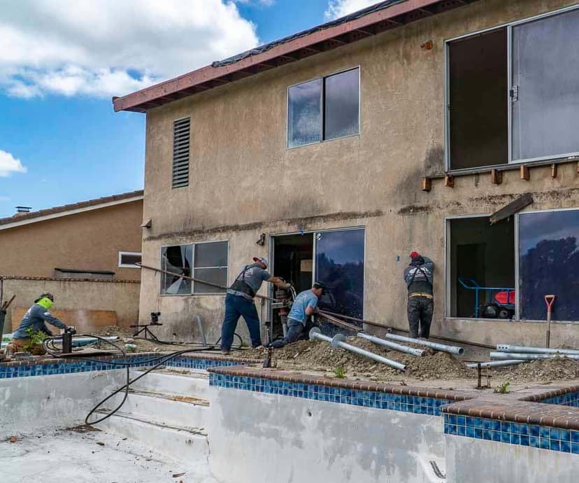 Dalinghaus Foundation Repair crew installing helical piers for house lifting and foundation repair at a residential property.