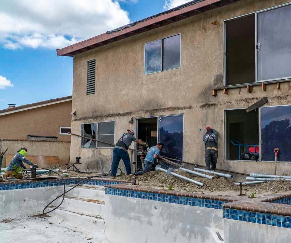 Dalinghaus Foundation Repair crew installing helical piers for house lifting and foundation repair at a residential property.