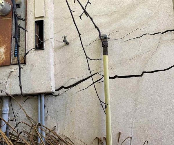 Dalinghaus Foundation Repair inspecting severe horizontal and structural cracks on an exterior stucco wall.