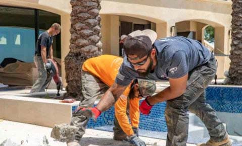 Dalinghaus Foundation Repair team members performing concrete work with a jackhammer during a pool deck repair project.