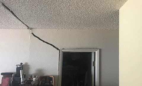 Dalinghaus Foundation Repair identifies prominent diagonal crack extending from popcorn ceiling down wall above door frame.