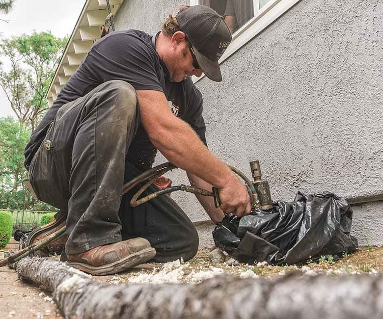 Dalinghaus Foundation Repair technician performing grout injection, also known as chemical grouting, at a house exterior.