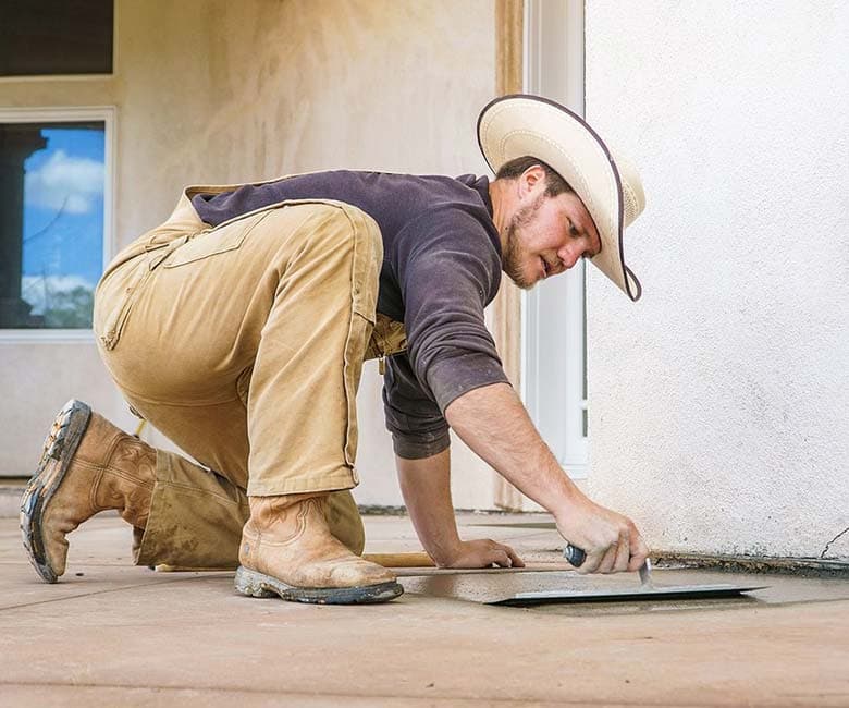 Dalinghaus Foundation Repair worker smoothing a concrete slab with a trowel, performing concrete repair.
