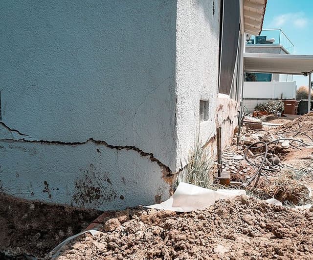 Dalinghaus Foundation Repair inspecting severe horizontal cracks on an exterior foundation wall during excavation.