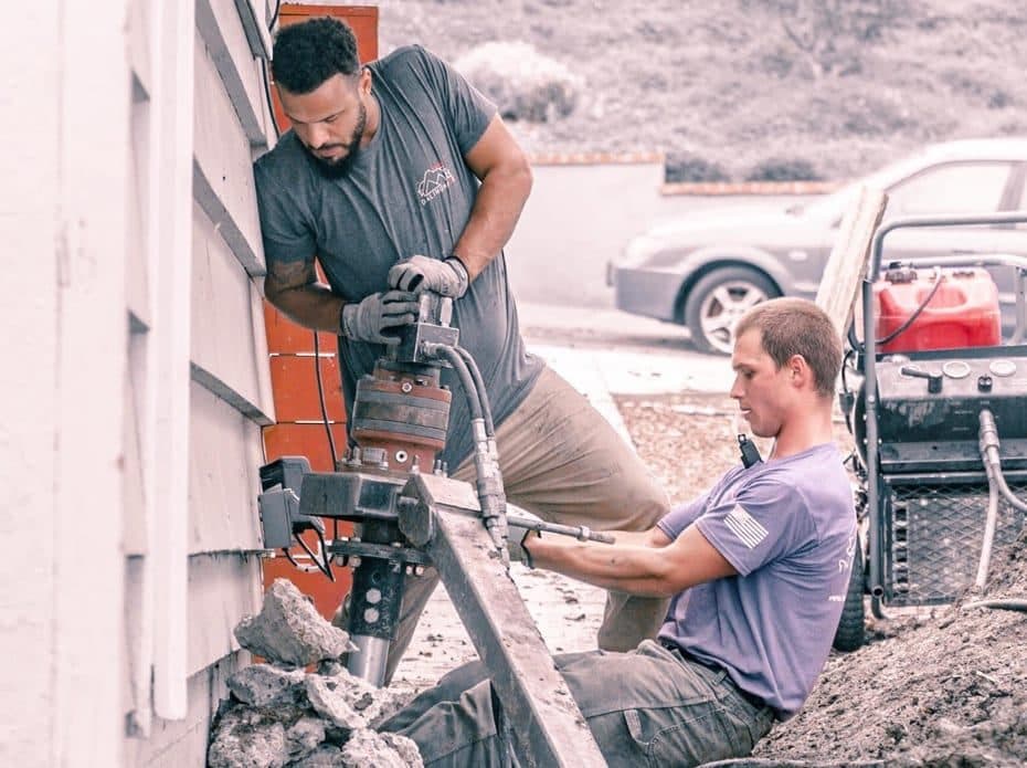Dalinghaus Foundation Repair team members installing steel foundation piers with hydraulic equipment.