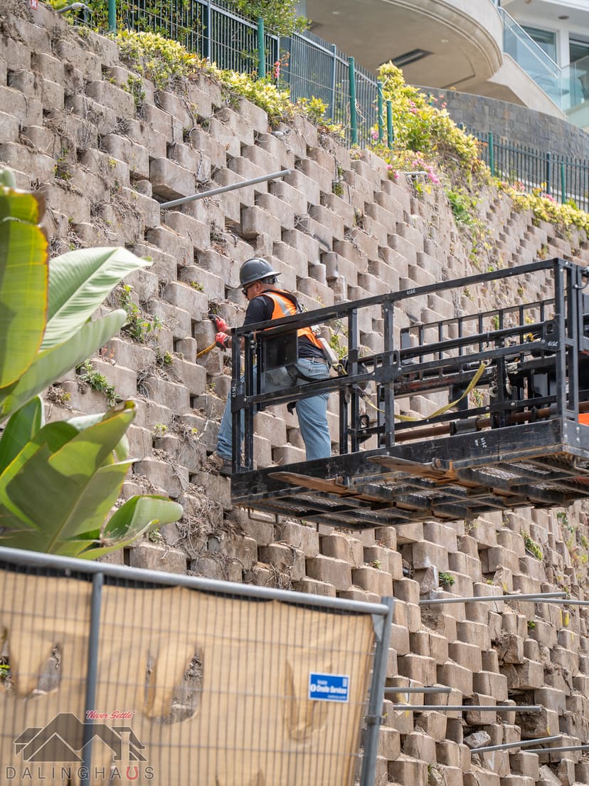 Dalinghaus Foundation Repair crew member installing tieback anchors to stabilize a residential retaining wall.