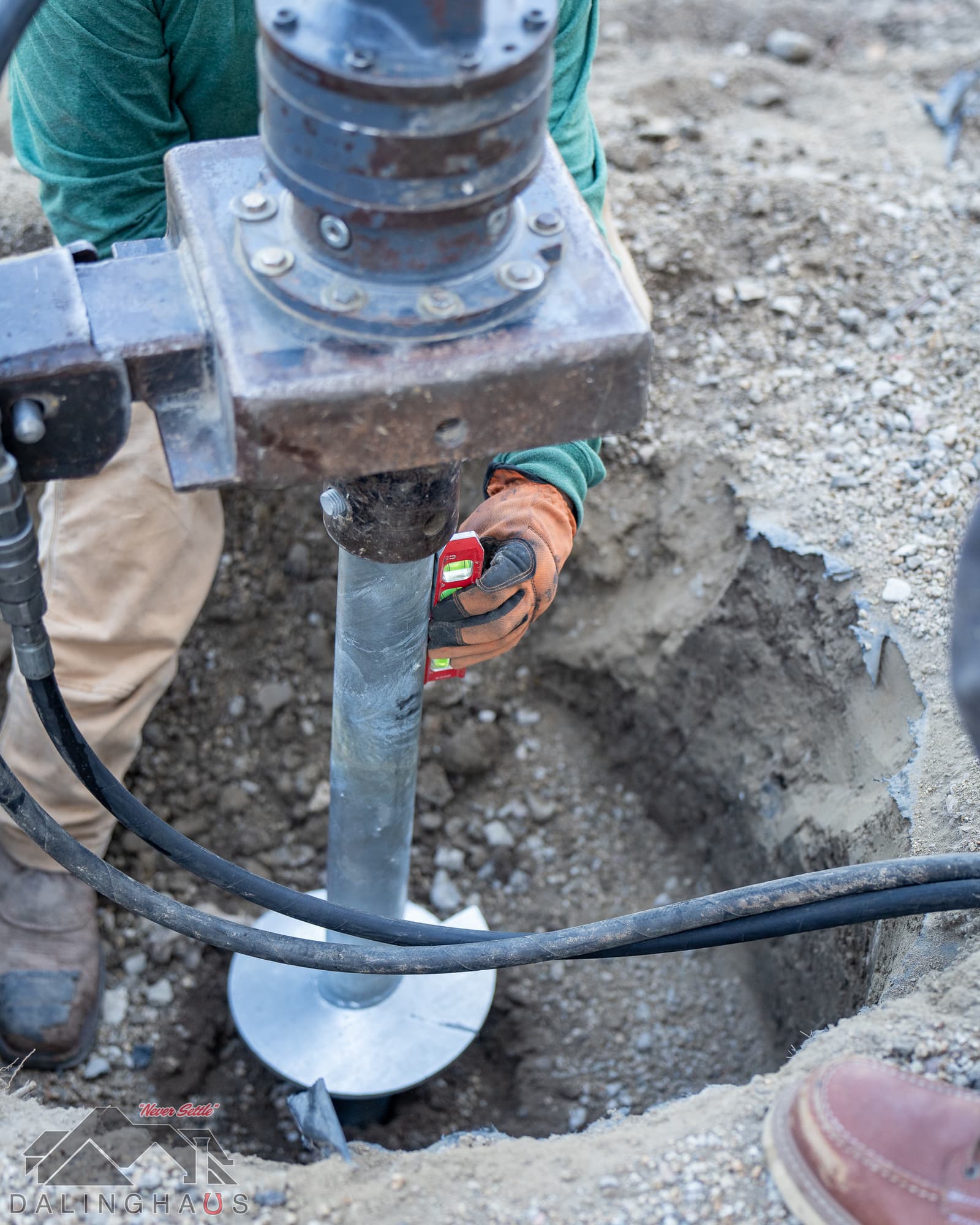 Dalinghaus Foundation Repair crew installing a push pier for foundation stabilization, using a leveling tool for precision.
