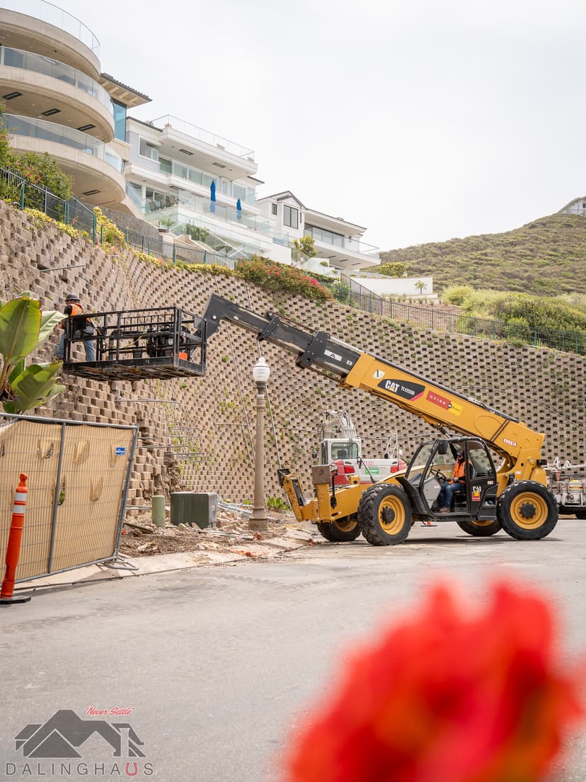 Dalinghaus Foundation Repair crew using a telehandler and man-basket to repair a concrete retaining wall in Dana Point.