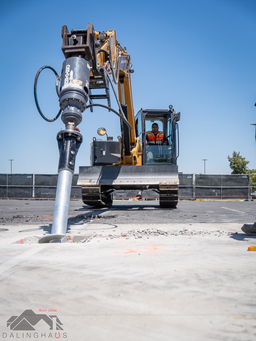 Dalinghaus Foundation Repair crew operating an excavator to install steel push piers for foundation stabilization.
