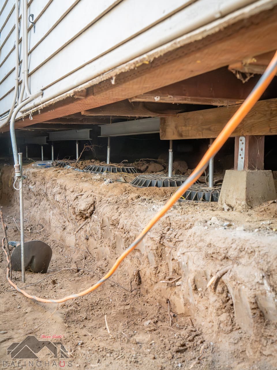 Dalinghaus Foundation Repair crew installing crawl space jacks and structural framing repair under a house.