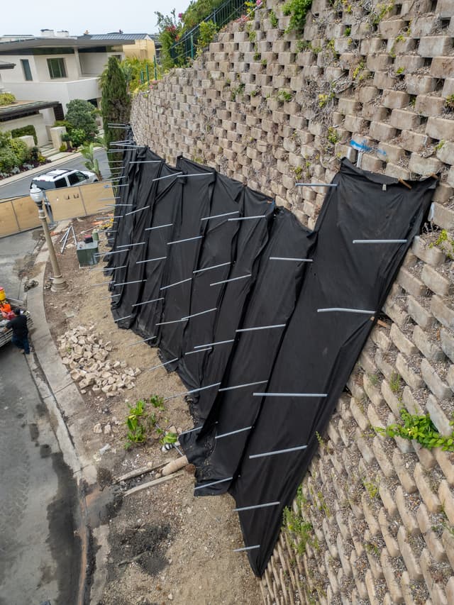 Dalinghaus Foundation Repair stabilizing a concrete block retaining wall with tieback anchors and geotextile fabric.
