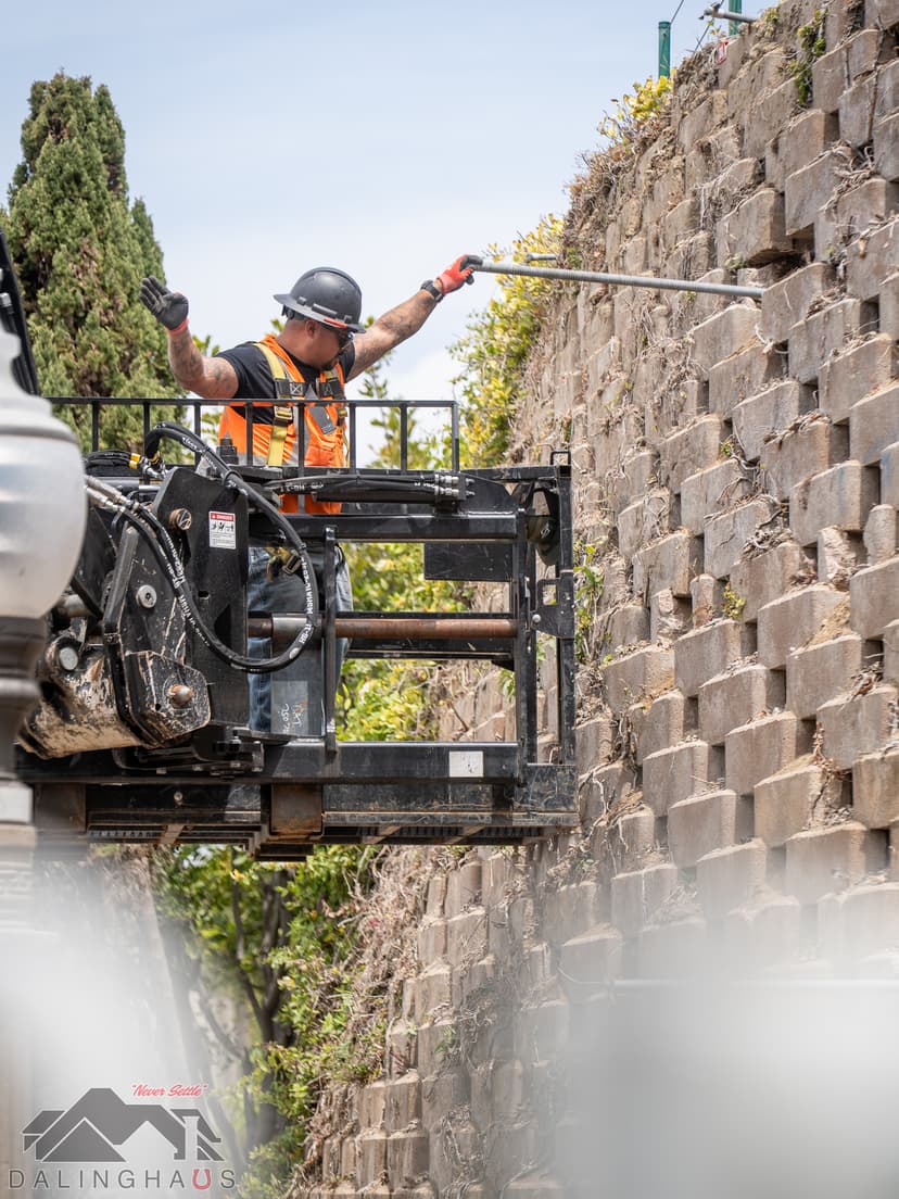 Dalinghaus Foundation Repair crew member installing wall anchor systems into a concrete retaining wall from a lift.