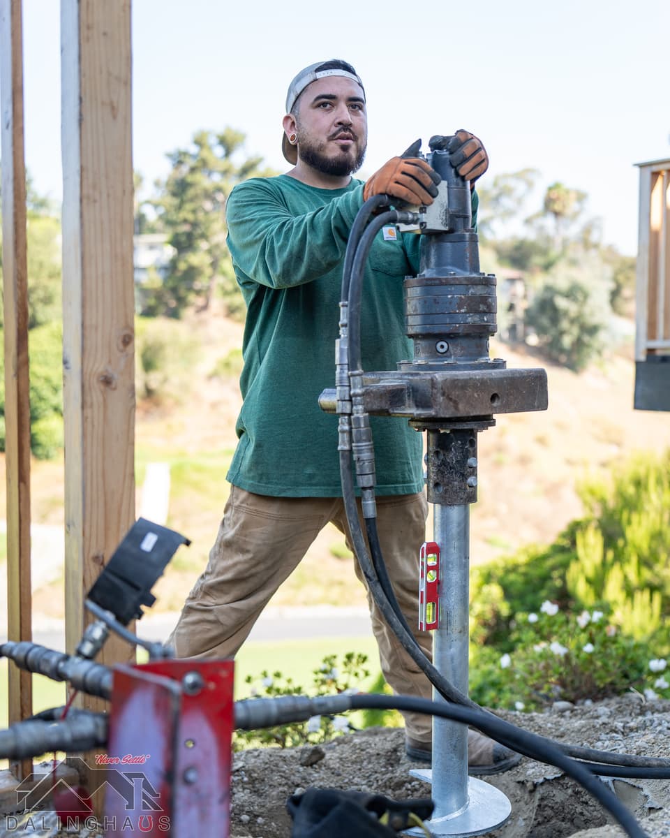 Dalinghaus Foundation Repair crew member installing a helical pier with a rotary drive head for foundation underpinning.