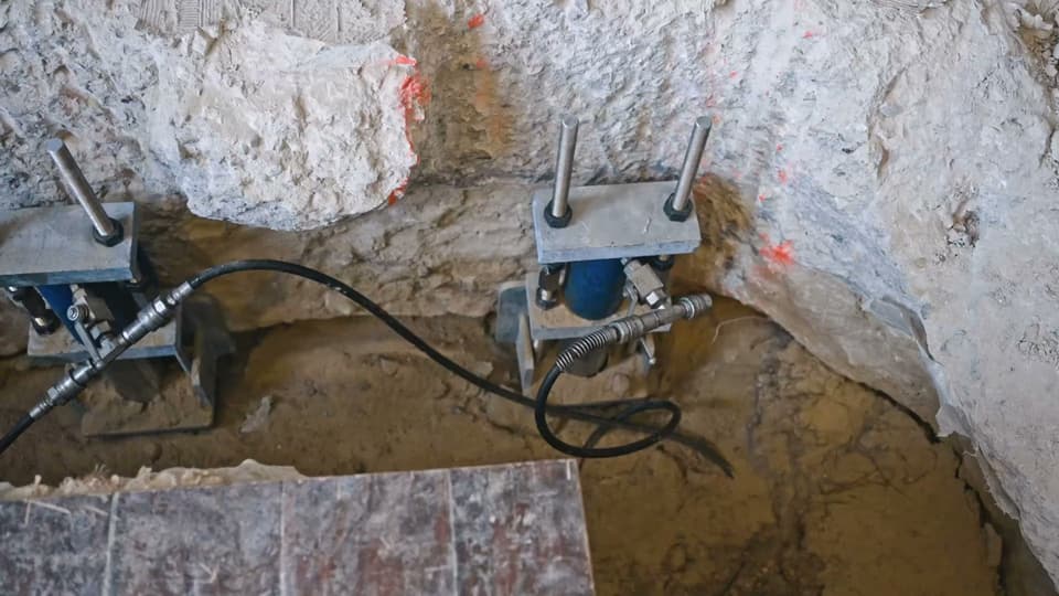 Dalinghaus Foundation Repair installing steel piers for foundation underpinning with hydraulic equipment in excavated soil.
