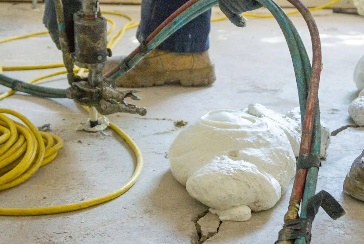 Dalinghaus Foundation Repair crew injecting polyurethane foam into a cracked concrete slab for void-filling.