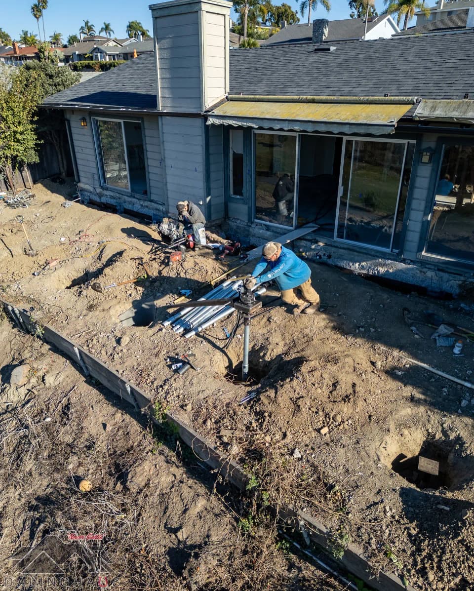 Dalinghaus Foundation Repair crew installing helical deck piers next to a house with an awning.