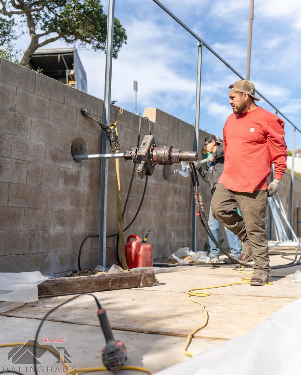 Dalinghaus Foundation Repair crew installing helical tieback anchors into a concrete block retaining wall.