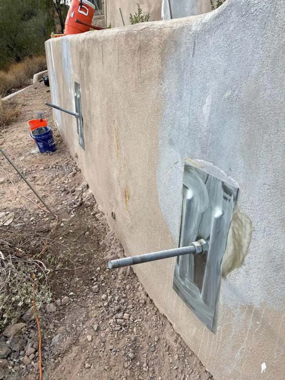 Dalinghaus Foundation Repair installing tieback anchors on a stucco retaining wall.