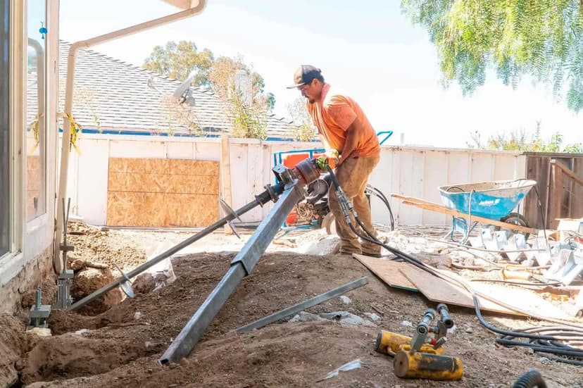Dalinghaus Foundation Repair technician installing helical piers with a rotary drive head for foundation stabilization.