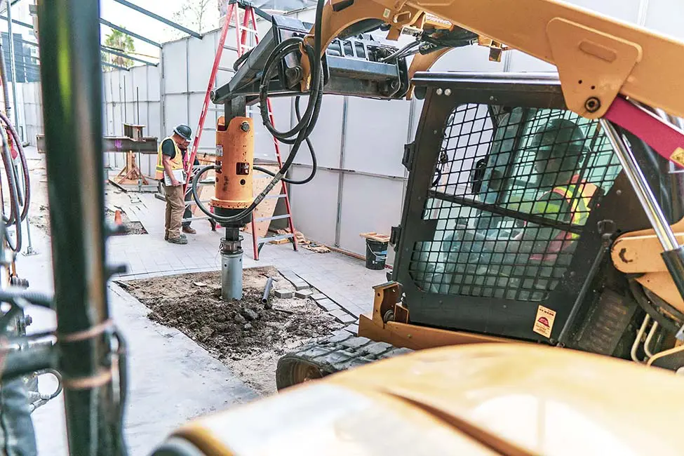 Dalinghaus Foundation Repair crew installing helical piles for new commercial construction with a skid steer and rotary