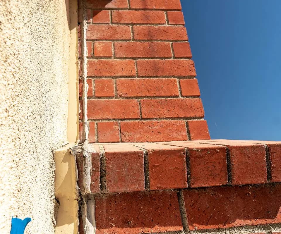 Dalinghaus Foundation Repair inspecting a brick chimney pulling away from a stucco wall.