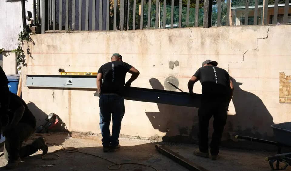 Dalinghaus Foundation Repair crew installing a steel I-beam for anchor reinforcement on a retaining wall with stair step