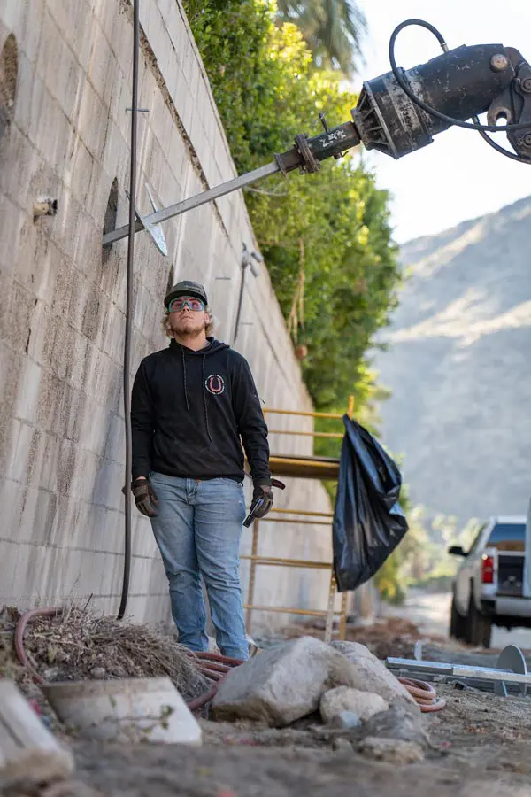 Dalinghaus Foundation Repair crew installing helical tie-back anchors into a retaining wall.